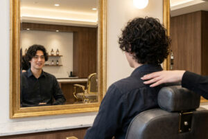 A young man admiring his freshly styled perm at a professional male parlour Gloucester.